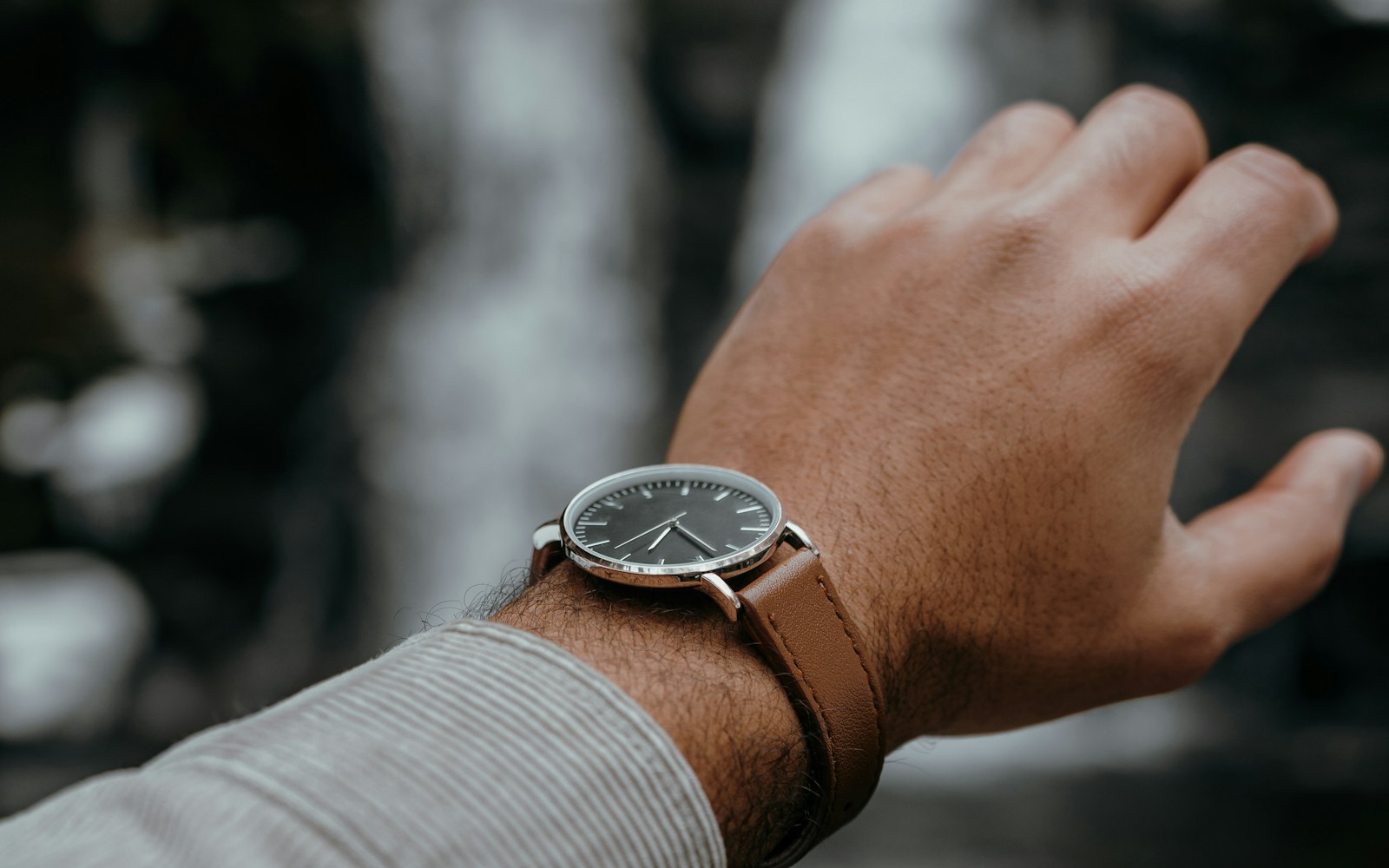 A person checking a simple quartz wristwatch during a weekday commute